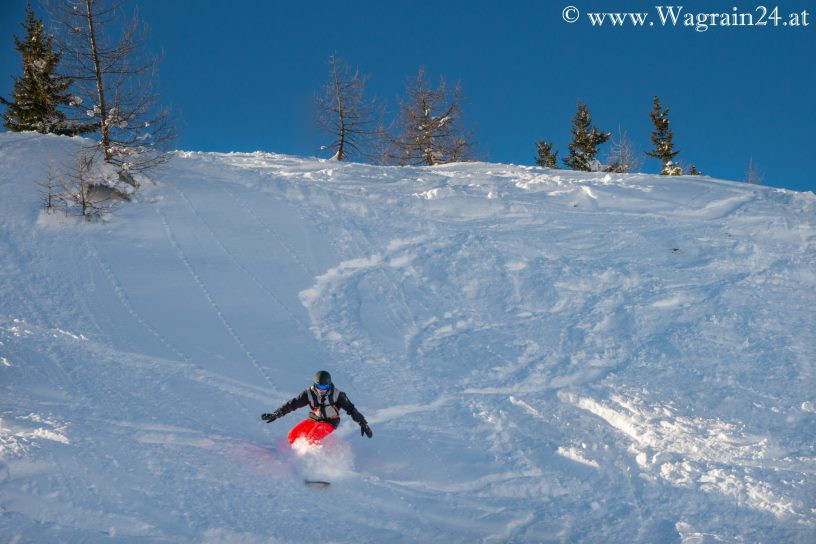 Snowobarder bei Tiefschnee-Abfahrt in Wagrain
